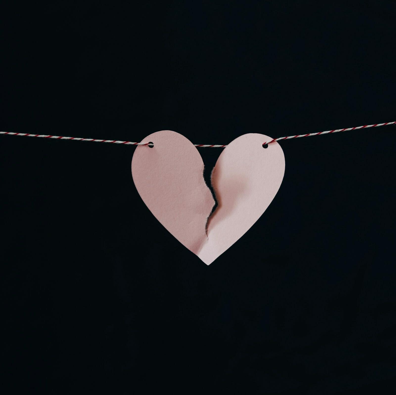 Gebrochenes Herz A paper heart on a string with a tear in the middle