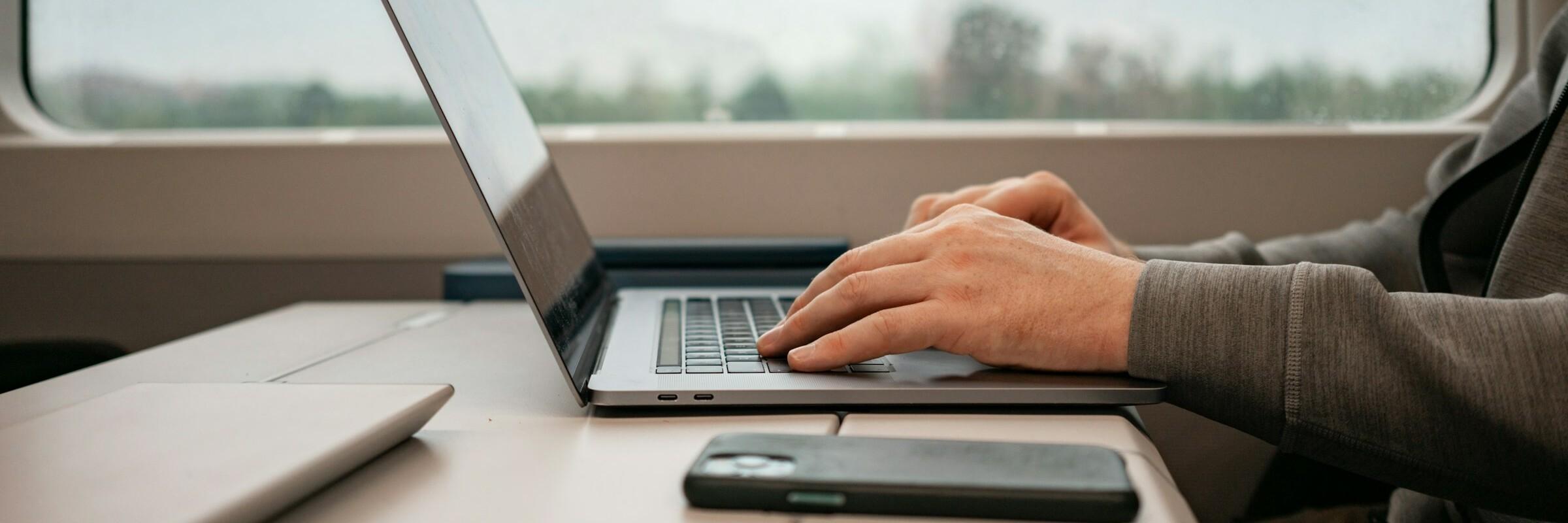 Mann mit Laptop mit Zug